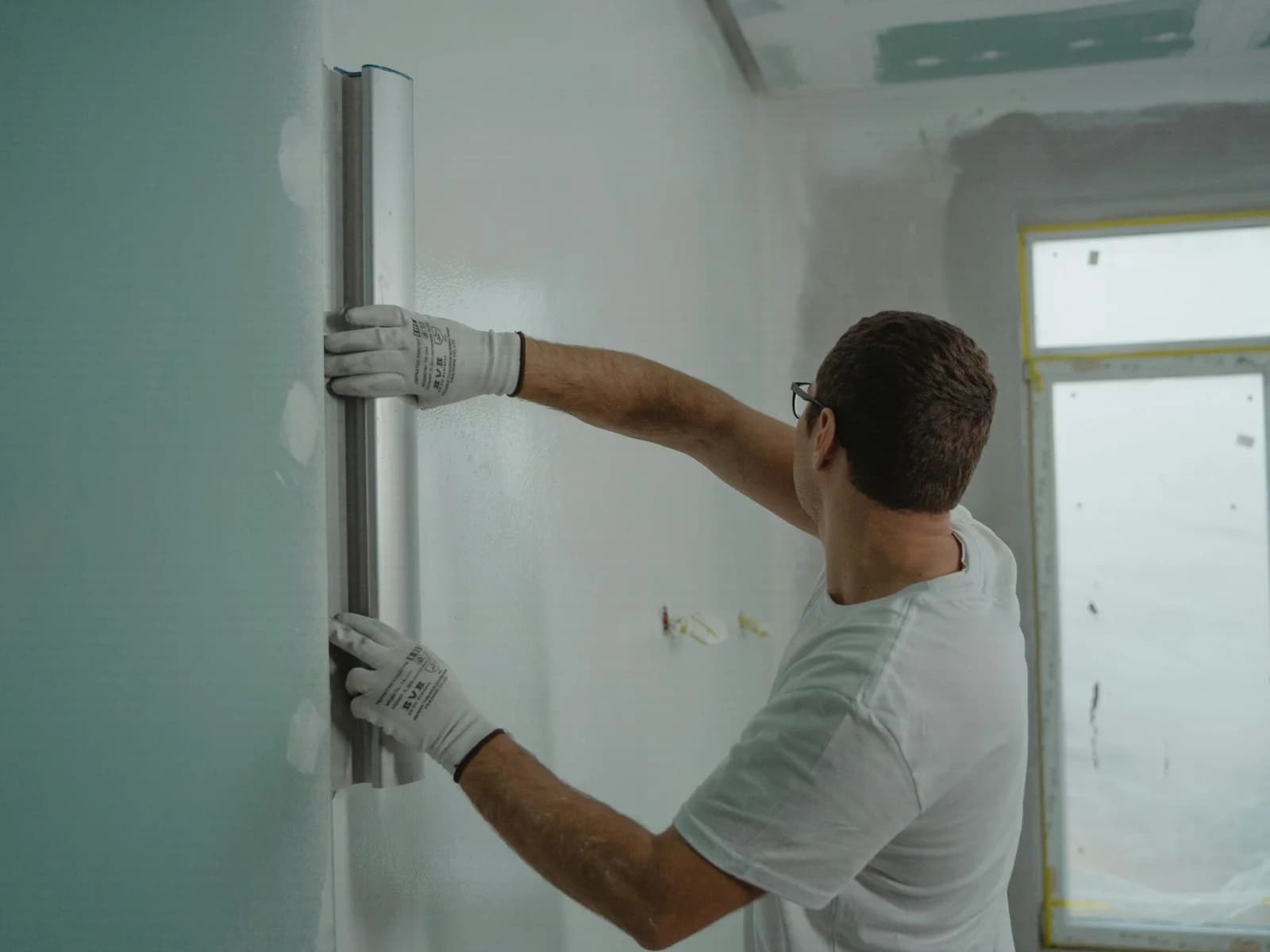 Maler bearbeitet eine Innenwand mit dem Spachtel