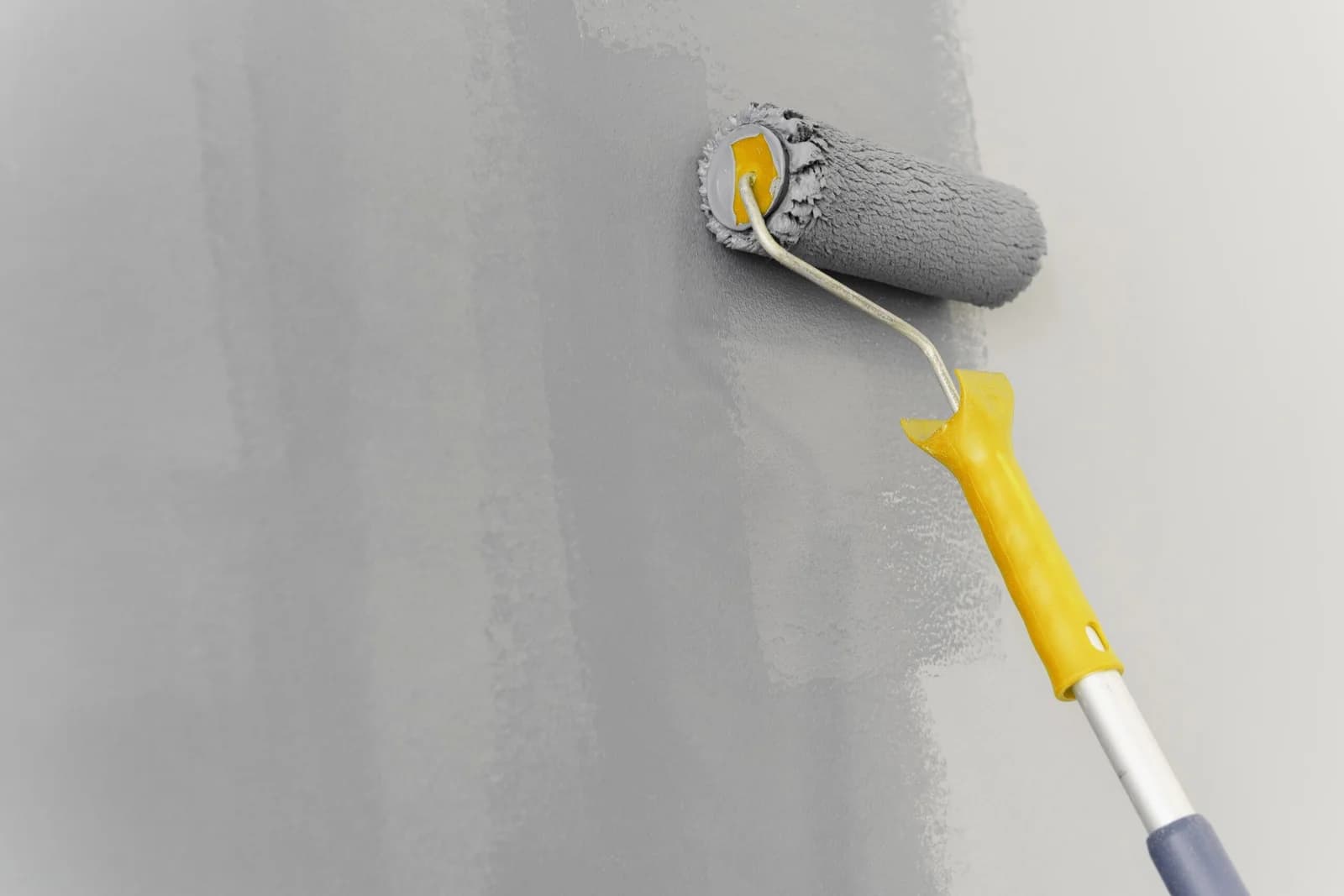 Maler trägt gelbe Farbe mit der Rolle auf